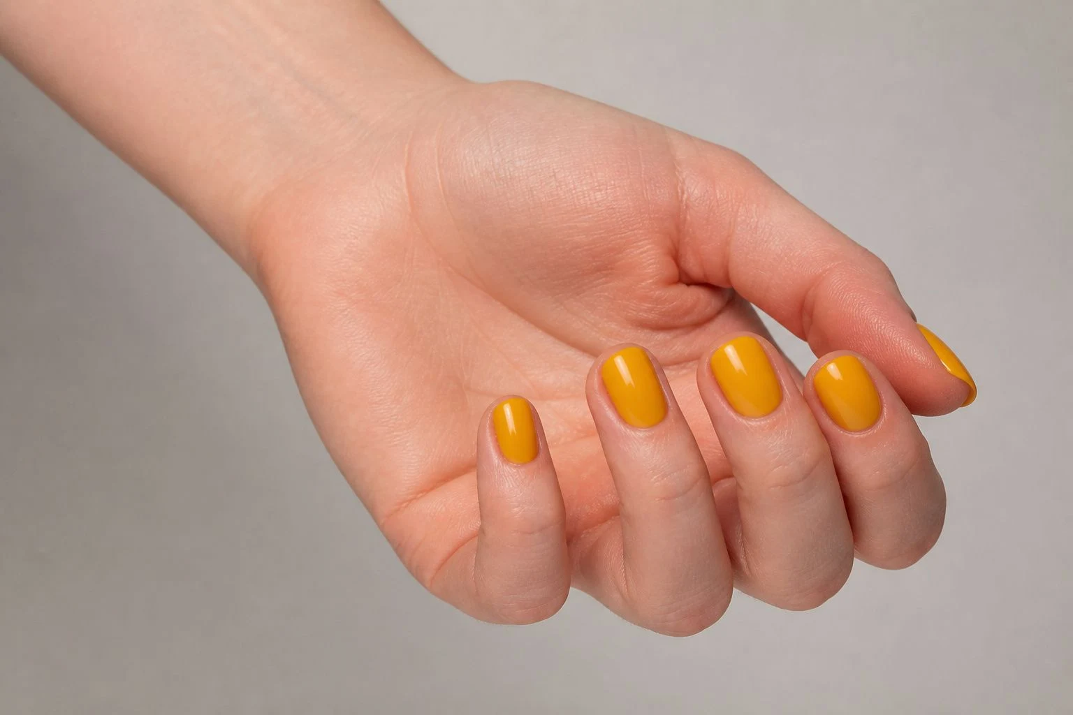 Golden yellow round nails in a curled hand pose with nail tops facing up