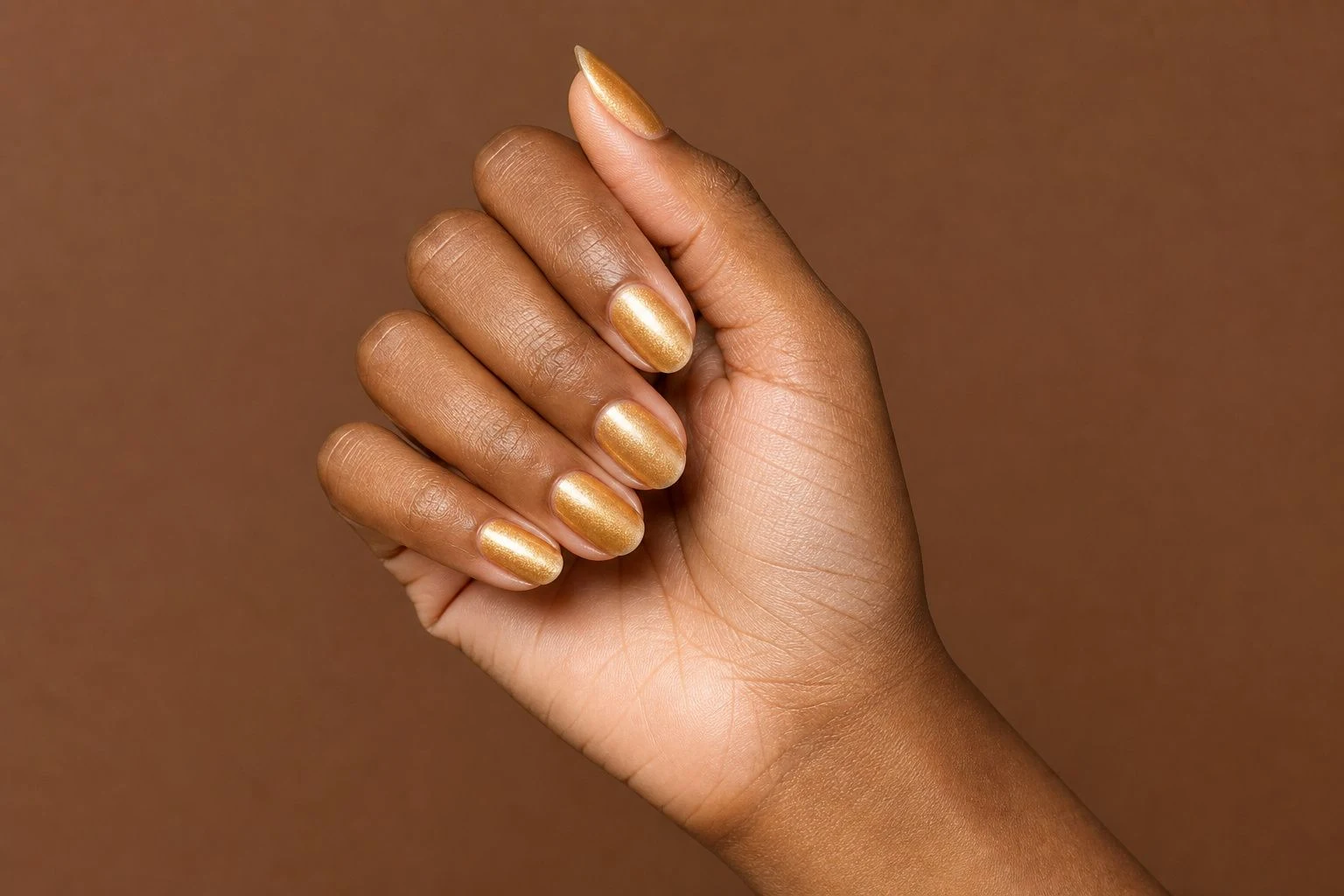 Honey gold shimmer round nails in a tilted curled hand pose
