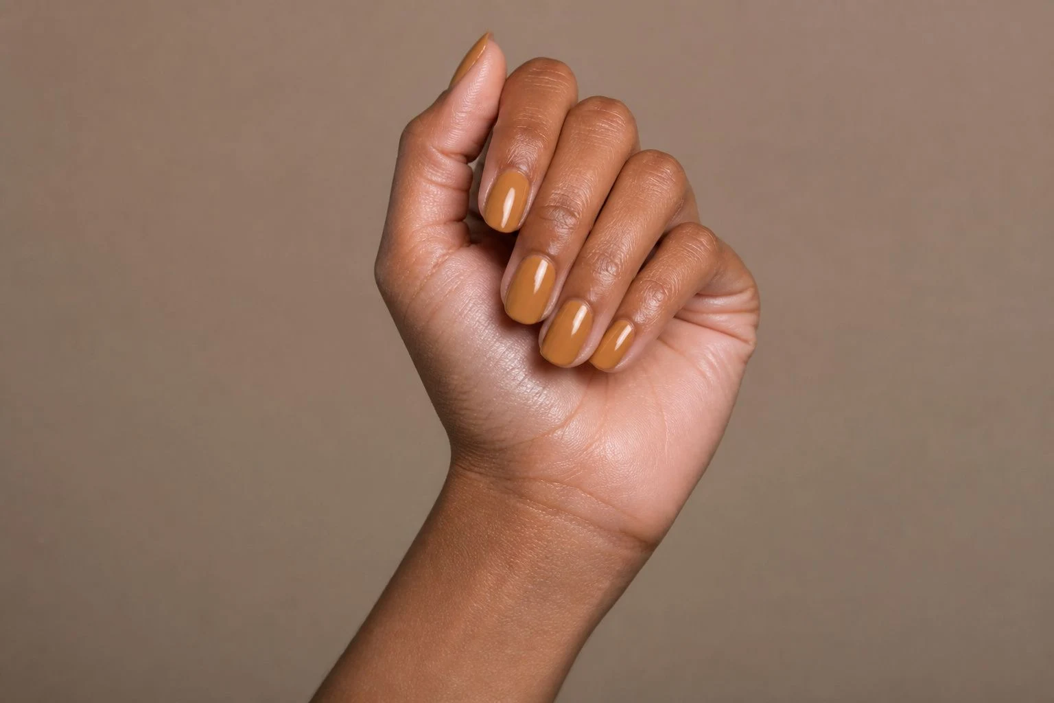 Dusty golden ochre round nails in an elevated curled hand pose