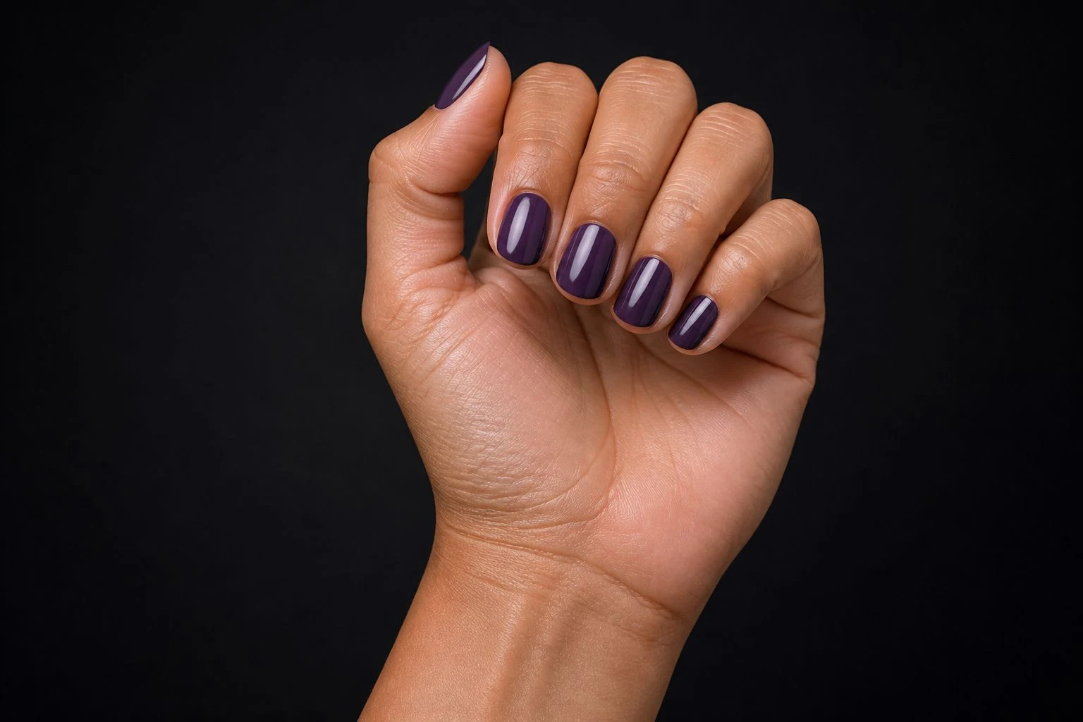 Dark cool toned purple round nails in a curled hand pose showing all five fingers