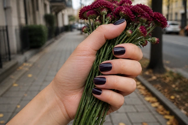 Aubergine fall nails on a woman’s complete hand in a natural everyday setting.