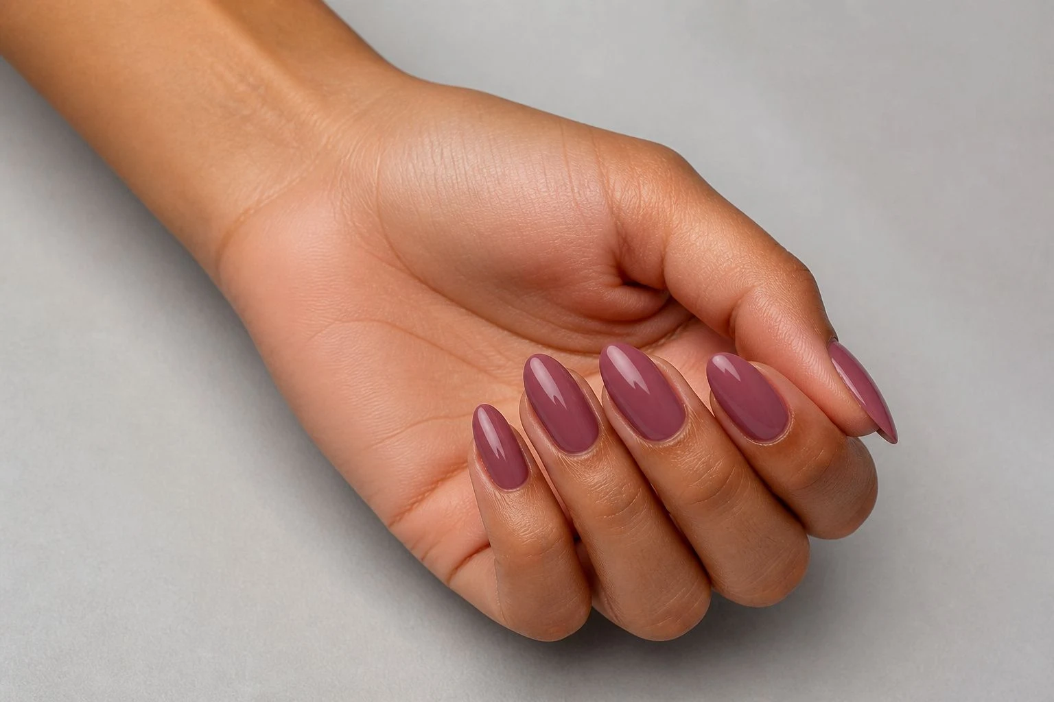 Mauve plum almond shaped nails in a curled hand pose with nail tops facing camera