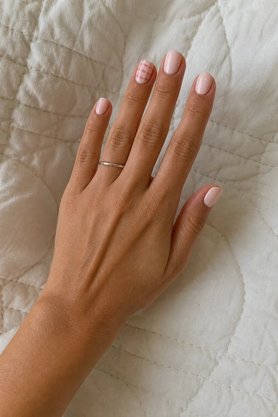 Blush gingham line manicure on short oval nails with glossy finish, three quarter hand pose, medium skin tone