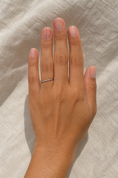 Minimal rose gingham line art on short square nude nails with glossy finish, relaxed hand pose, medium olive skin tone