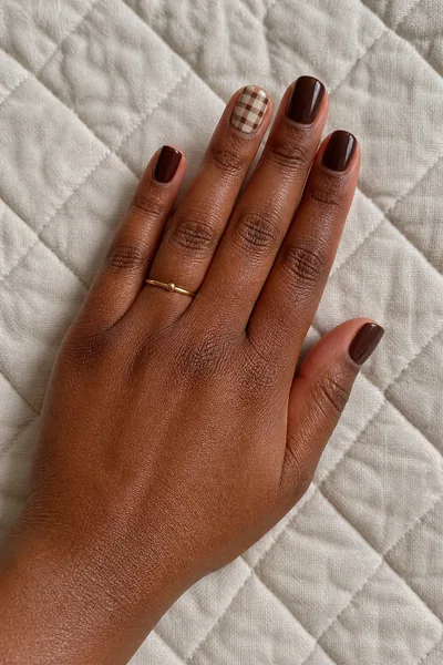 Chocolate and cream gingham set on short square nails with glossy finish, relaxed diagonal hand pose, warm deep skin tone