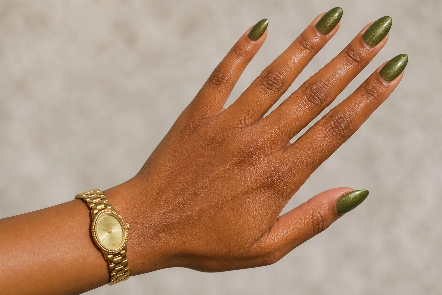 Olive green nails with subtle shimmer and a slim gold watch, diagonal hand pose