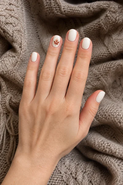Cream and rust harvest accent on short oval nails with glossy finish, relaxed hand pose, fair skin tone