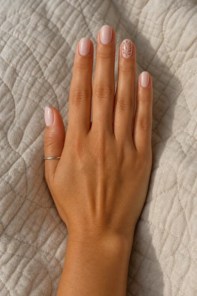 Blush nails with harvest leaf art on short oval shape, glossy three quarter hand pose, medium skin tone