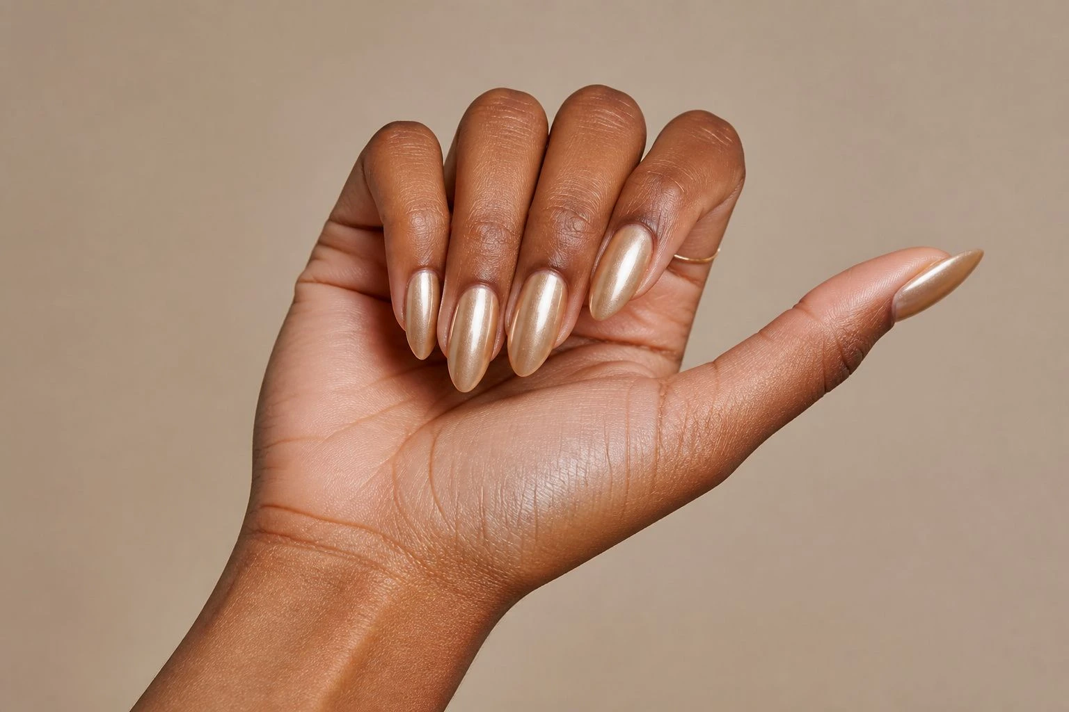 Long almond shaped champagne gold chrome nails with a delicate gold ring, Christmas nail idea