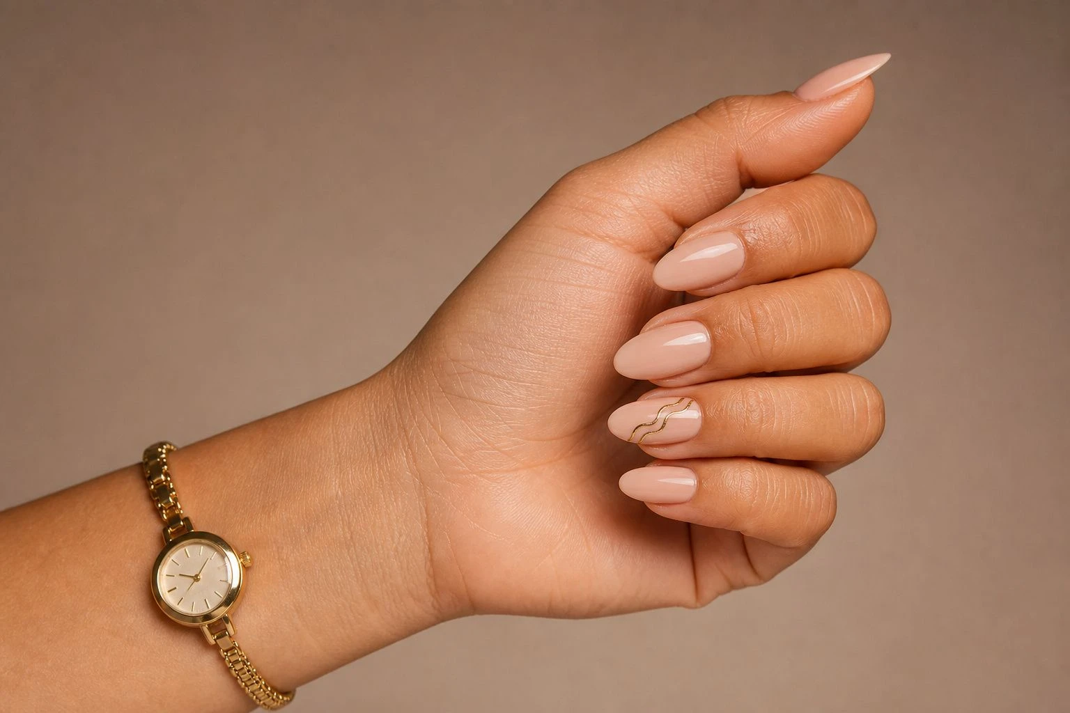 Glossy nude almond nails with an abstract gold swirl accent nail and a slim gold watch, Christmas nail idea