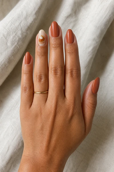 Terracotta pumpkin pie art on medium almond nails with glossy finish, fingers angled toward daylight, light skin tone