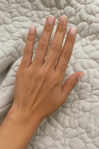 Blush pumpkin pie illustration manicure on medium oval nails with glossy finish, open hand pose, medium skin tone