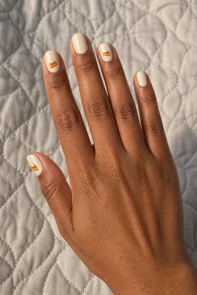 Mini pumpkin pie illustrations on short square nails with glossy finish, relaxed five finger pose, fair skin tone