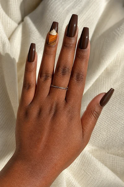 Deep cocoa pumpkin pie manicure on long coffin nails with glossy finish, angled hand pose, light olive skin tone