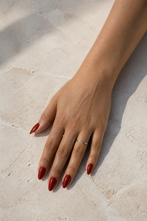 red acrylic French tip almond nails on a warm tan hand with visible wrist