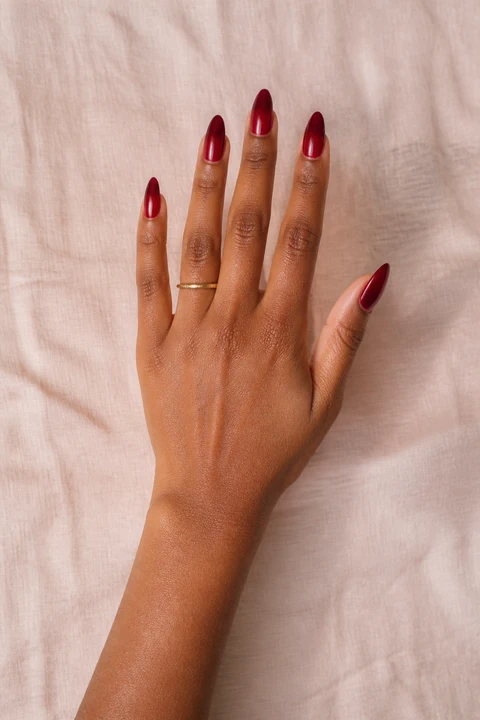 red reverse French acrylic nails with cuticle arcs on a medium brown hand with visible wrist and forearm