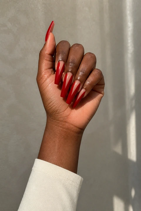 glossy red acrylic nails with a fine gold stripe on an olive skin tone hand with visible wrist