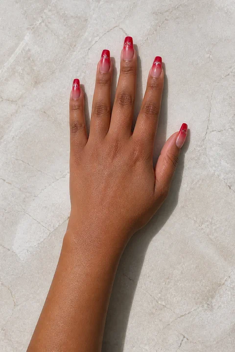 red acrylic ombre nails fading into a soft nude shade on a medium deep hand with visible wrist