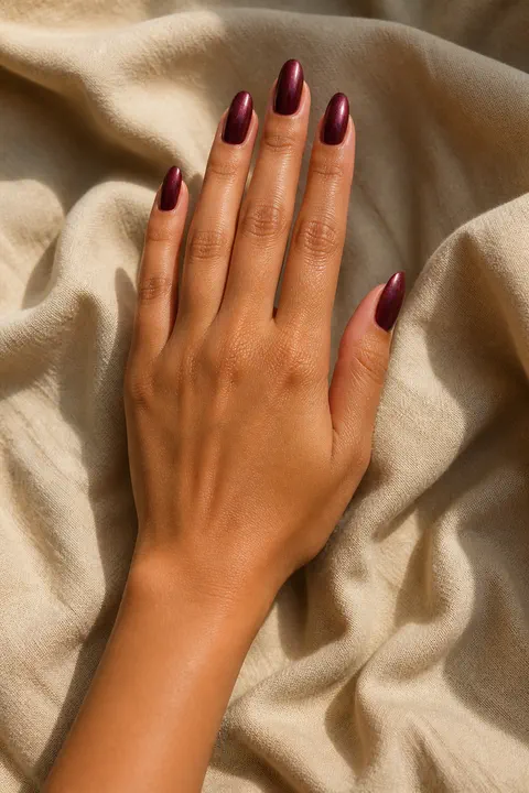 deep garnet acrylic nails with a velvet magnetic finish on a rich brown hand with visible wrist and forearm