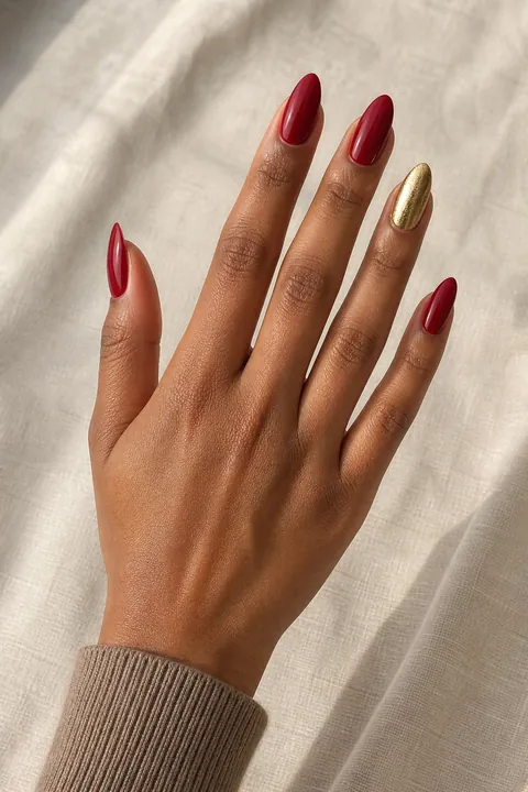 Soft metallic true-red medium almond nails on a medium olive hand in a relaxed open pose with a stitched cream cuff and tiny silver ring