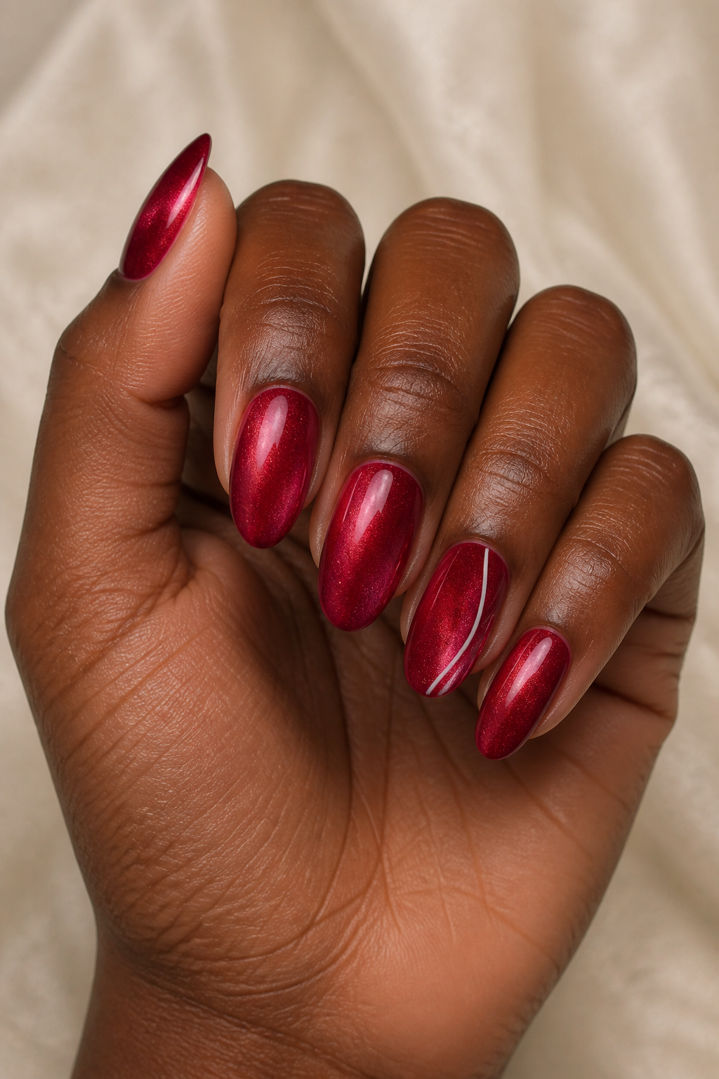 Ruby velvet almond Christmas nails with a fine candy-cane accent.