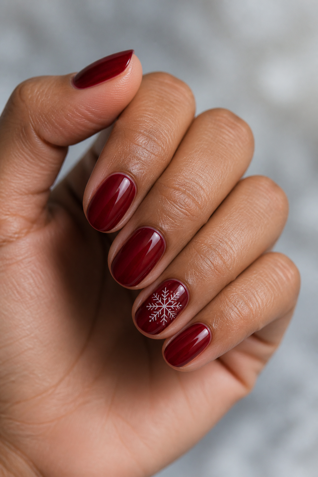 Cranberry jelly short oval Christmas nails with a snowflake accent.