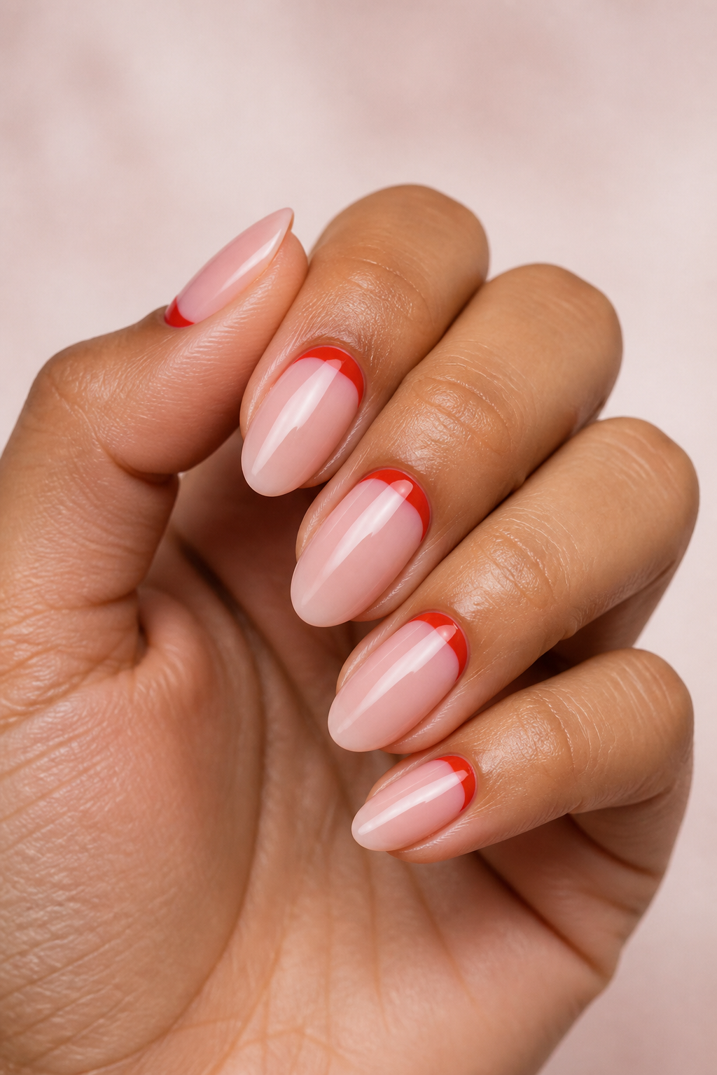 Sheer blush Christmas nails with red reverse-French crescents.