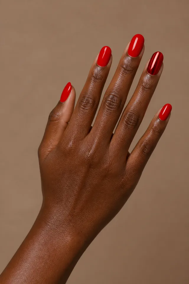 glossy red nails with a red chrome accent nail on a warm brown hand