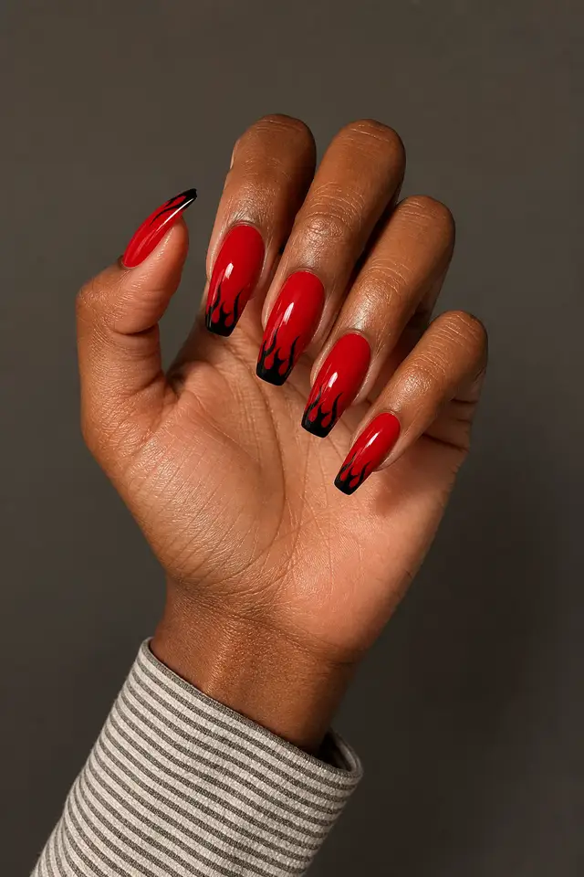 deep red coffin nails with subtle spiderweb art on a deep brown hand in daylight