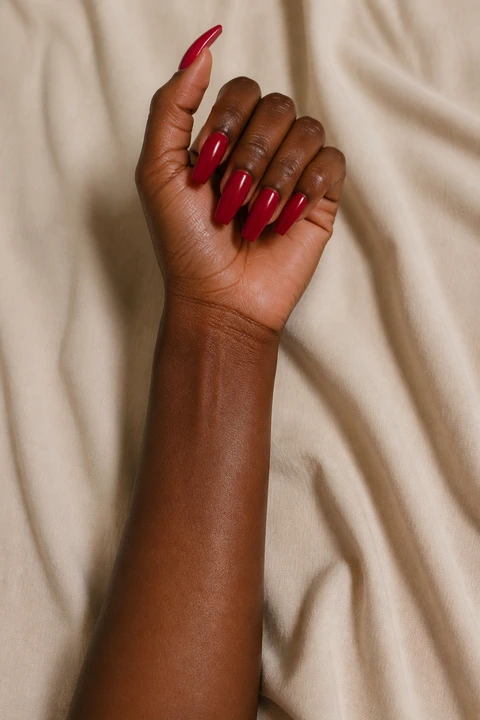 glassy scarlet red nails on a light golden hand with visible wrist and forearm