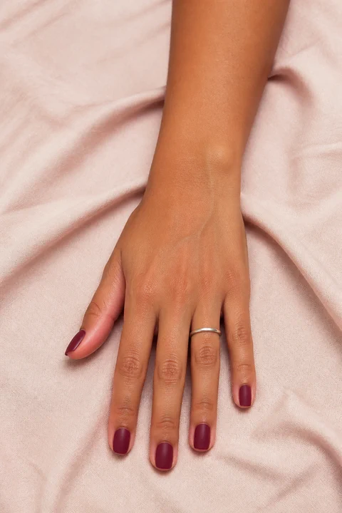 matte burgundy red short square nails on a medium deep hand with visible wrist