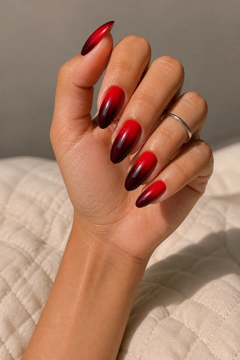 poppy red fading into wine glossy almond nails on a tan skin tone hand with visible wrist