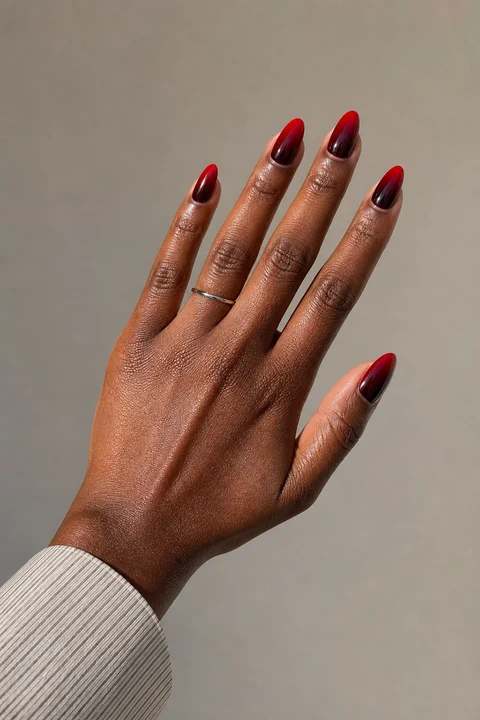 reverse wine to scarlet glossy ombre almond nails on a tan hand with visible wrist