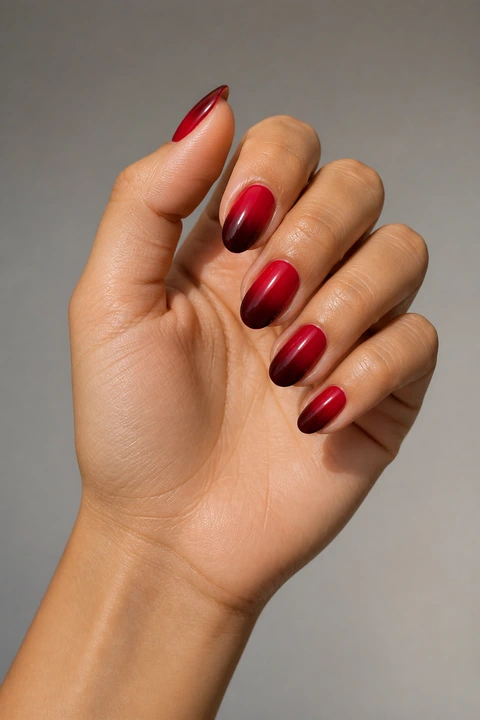 natural glossy nail base fading to soft red tips on a rich brown hand with visible wrist