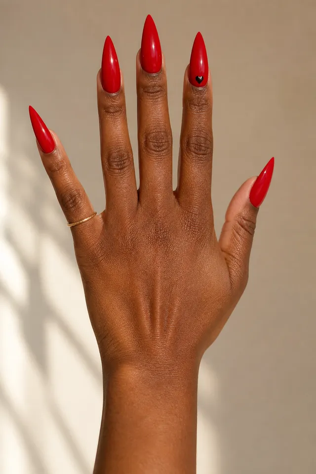 bright red glossy stiletto nails on a deep brown hand with fingers spread and visible wrist in daylight