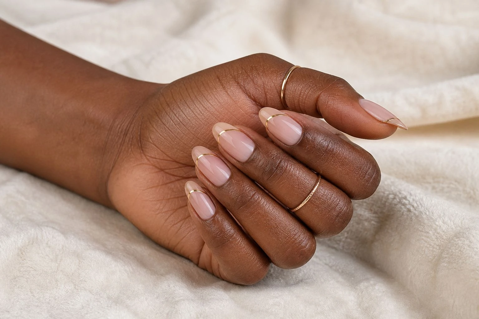 Sheer nude nails with a thin copper foil line accent and two delicate gold rings, simple Christmas nail idea
