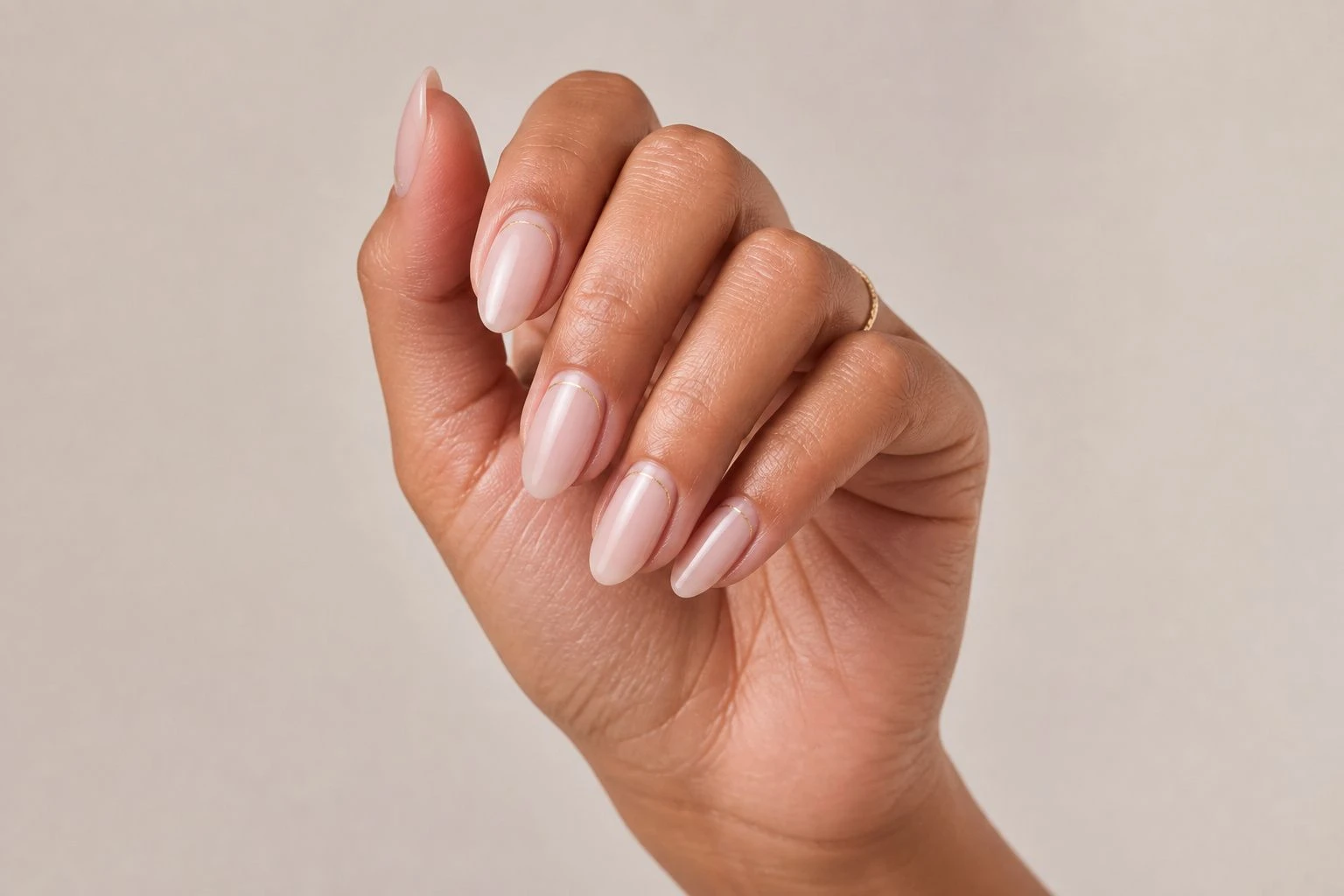 Sheer nude nails with a fine gold thread line negative space accent and a gold ring, simple Christmas nail idea