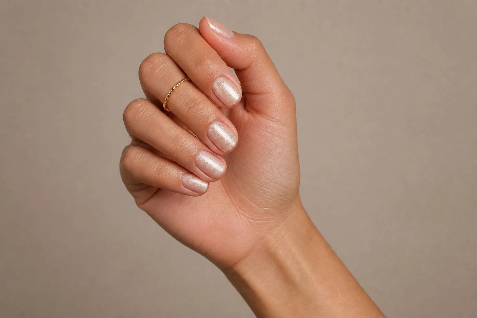 Short oval icy champagne shimmer nude manicure with two delicate gold rings, simple Christmas nail idea