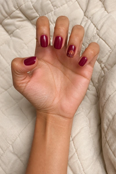 Cranberry turkey feather manicure on short round nails with glossy finish, open hand pose, rich dark brown skin tone