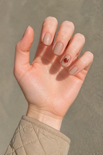Simple rust turkey silhouette on short oval nude nails, glossy diagonal hand pose, fair skin tone