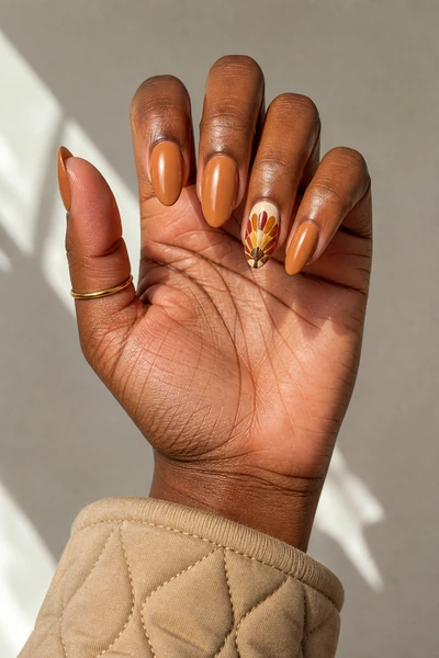 Caramel almond nails with detailed turkey feather fan, glossy finish and lifted hand pose, deep brown skin tone