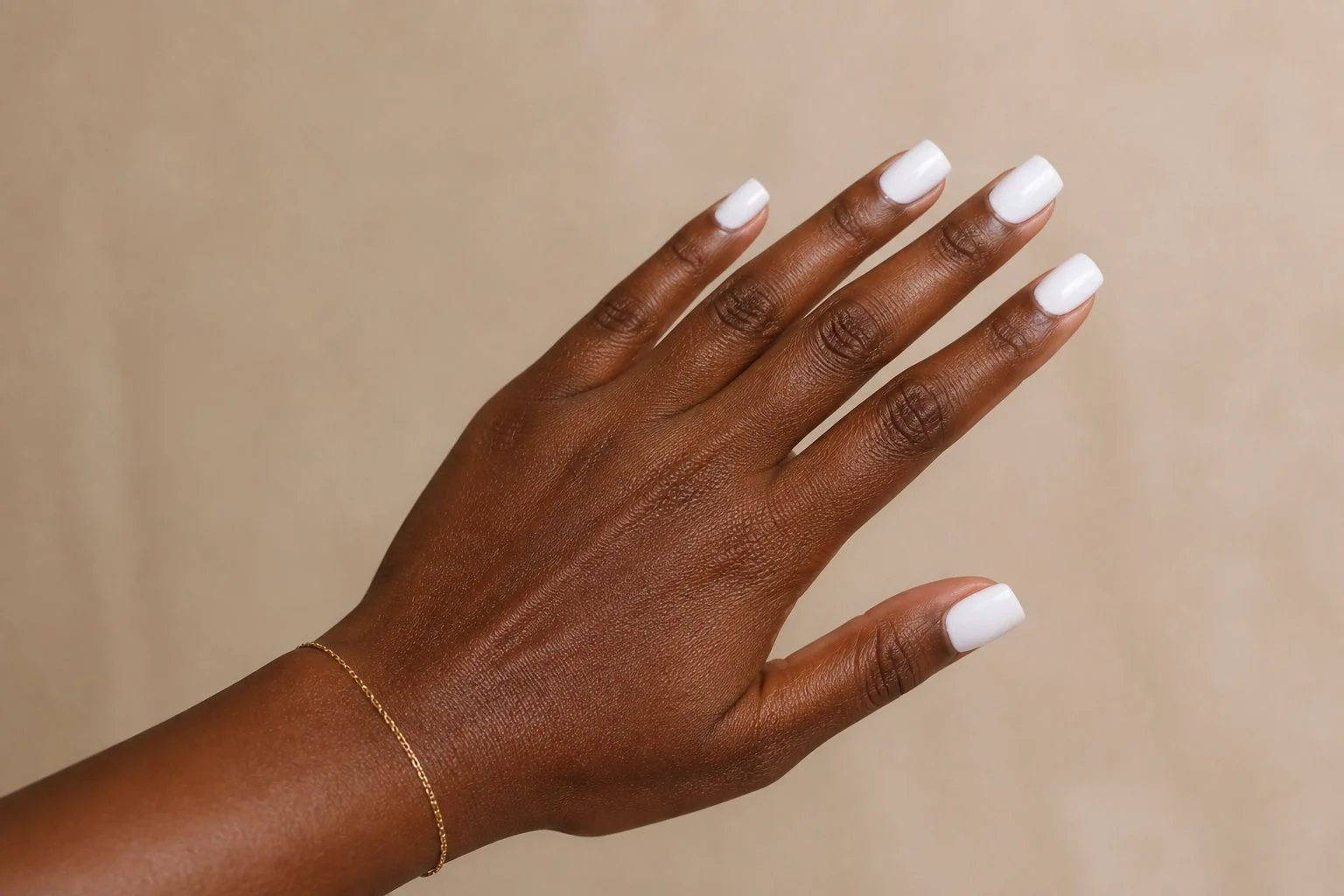 Bright white square Christmas nails with a delicate gold bracelet, natural fan pose