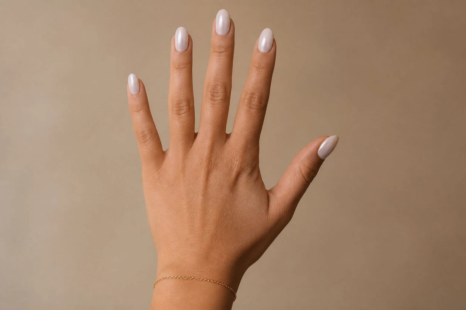 Pearl white oval Christmas nails with a delicate gold bracelet, open palm pose
