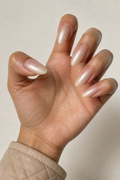 Champagne ombre acrylic almond nails on an open palm and knuckle angle with visible wrist, tan skin tone, soft daylight