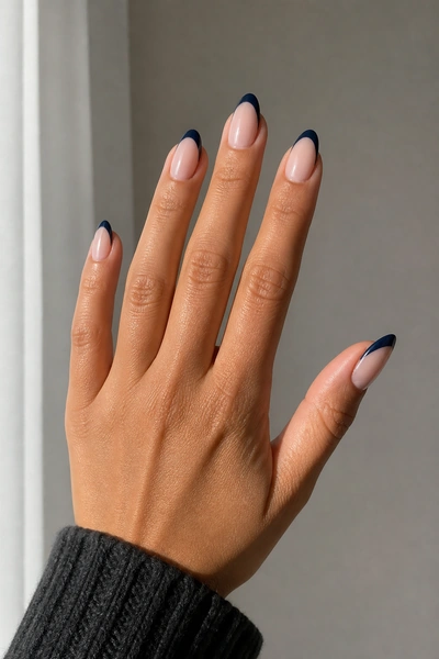 Midnight navy French tip nails on a tan skin tone hand in a side angled open pose with visible wrist and short partial forearm, natural daylight