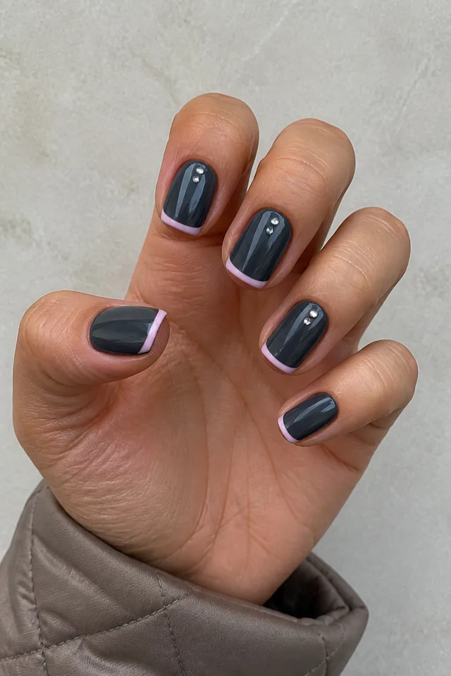 Charcoal slate glossy medium square nails with blush-pink micro-French tips and silver dots on olive beige skin, shown in a relaxed three-quarter arched pose with a short partial wrist
