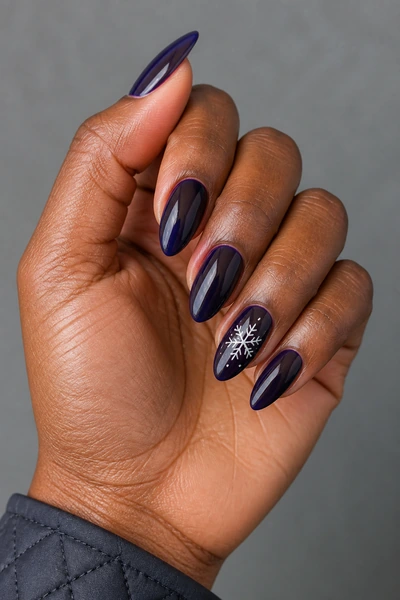 White snowflake accent nails on a deep brown skin tone hand in a relaxed side angle with visible wrist and short partial forearm, natural daylight