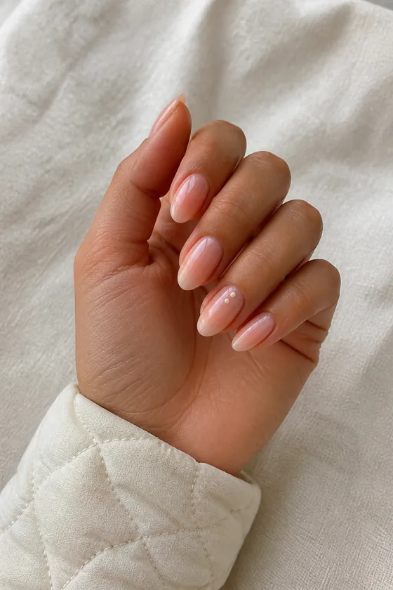 Tan skin hand in a gentle curled pose with warm champagne pearl oval bridal nails and a subtle shimmer finish