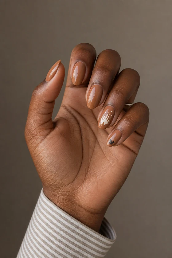 Rich dark brown hand with glossy caramel nude almond nails, white castle sparkle art, and a tiny Mickey accent in daylight