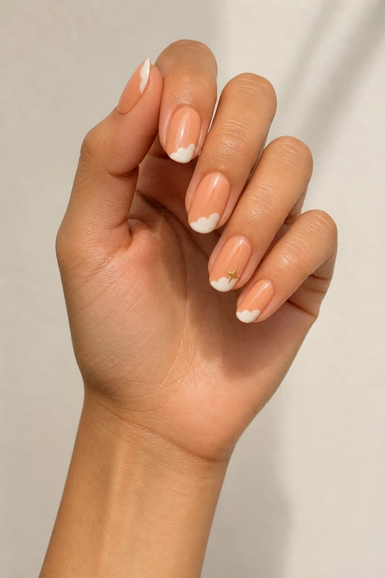 Tan skin hand with glossy peach almond nails, soft white cloud tips, and one tiny gold star in daylight